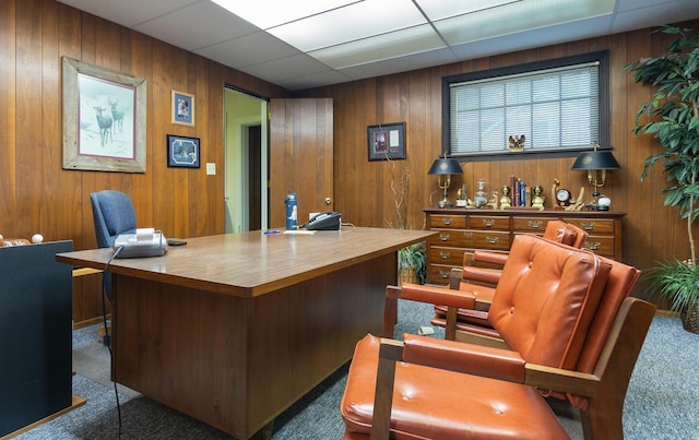 carpeted home office with a drop ceiling and wood walls