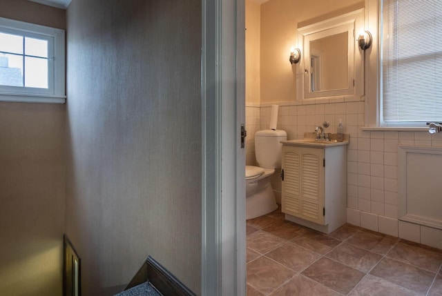 bathroom with tile patterned floors, vanity, toilet, and tile walls