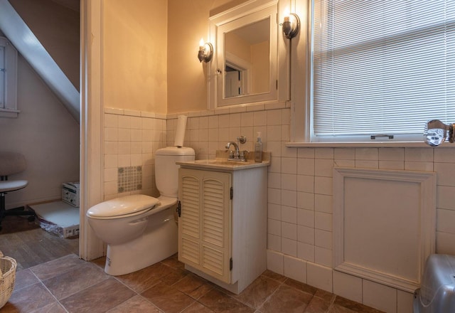 bathroom featuring vanity, a healthy amount of sunlight, toilet, and tile walls