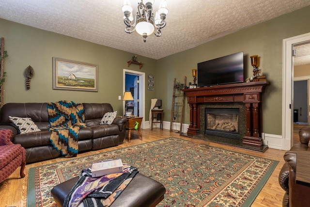 living room featuring wood-type flooring, a textured ceiling, and a notable chandelier