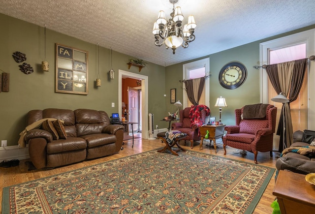 living room featuring wood-type flooring, a textured ceiling, and an inviting chandelier