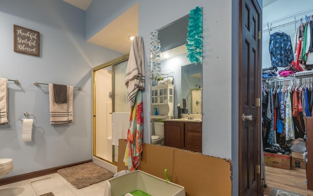 bathroom featuring wood-type flooring, vanity, toilet, and walk in shower