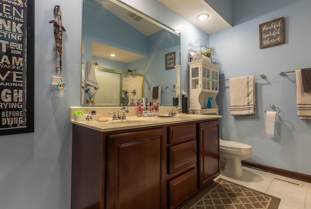 bathroom with toilet, tile patterned flooring, vanity, and walk in shower