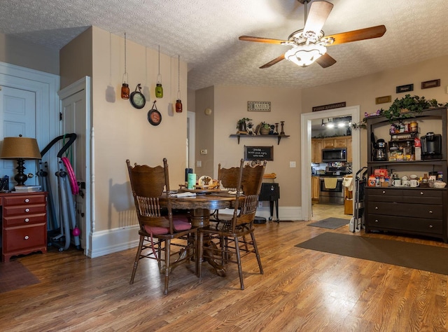 dining room with ceiling fan, hardwood / wood-style floors, and a textured ceiling