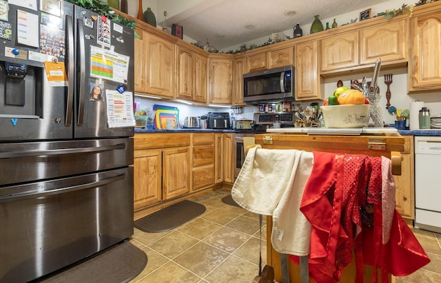 kitchen with a textured ceiling, stainless steel appliances, and light tile patterned flooring