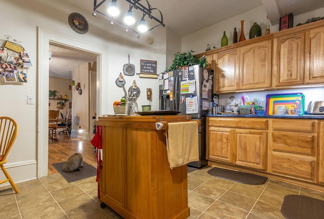 kitchen with tile patterned floors, a textured ceiling, and stainless steel refrigerator with ice dispenser