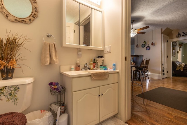 bathroom with vanity, a textured ceiling, ceiling fan, hardwood / wood-style floors, and toilet