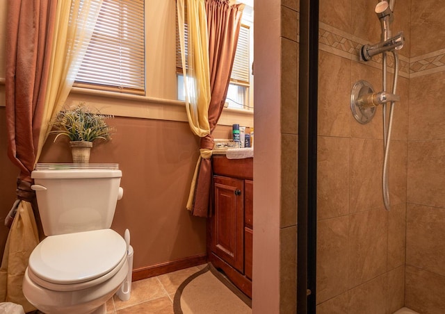 bathroom with tile patterned flooring, vanity, toilet, and a tile shower