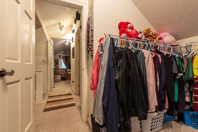 walk in closet with lofted ceiling and light carpet