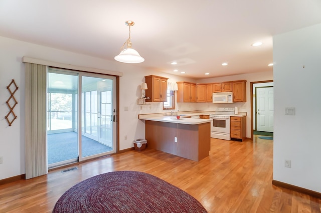 kitchen with kitchen peninsula, plenty of natural light, light hardwood / wood-style floors, and white appliances