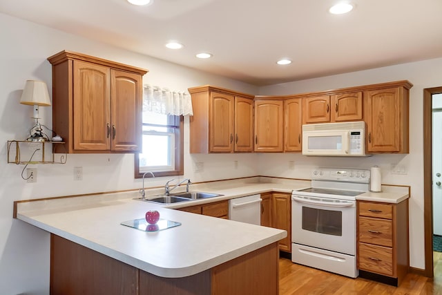 kitchen featuring kitchen peninsula, sink, light hardwood / wood-style floors, and white appliances