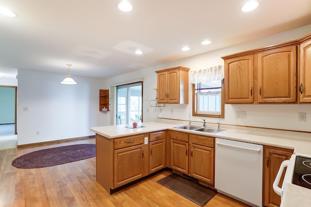 kitchen with kitchen peninsula, white dishwasher, sink, decorative light fixtures, and light hardwood / wood-style flooring