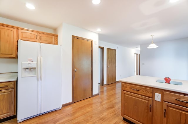 kitchen with pendant lighting, white refrigerator with ice dispenser, and light hardwood / wood-style flooring