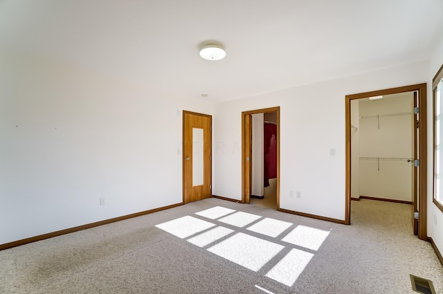 unfurnished bedroom with light carpet, a spacious closet, and a closet