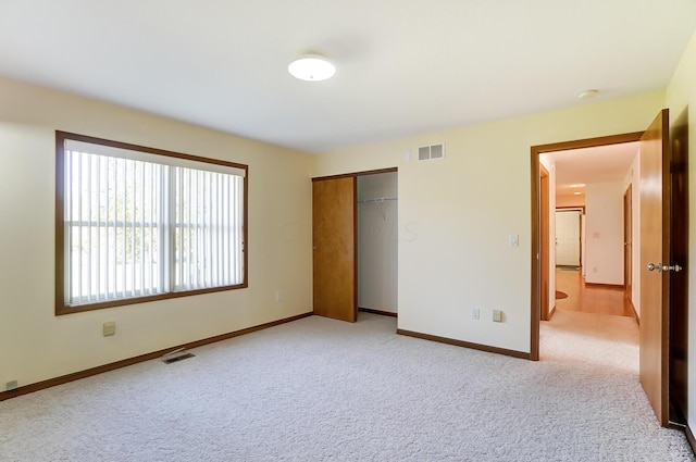 unfurnished bedroom featuring light carpet and a closet