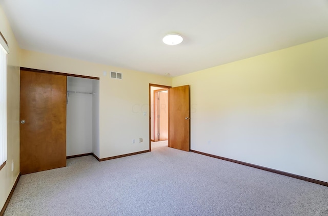 unfurnished bedroom with light carpet and a closet