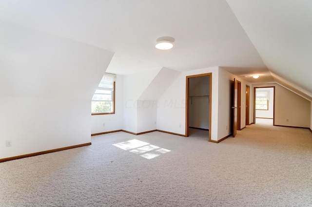 bonus room with light colored carpet and lofted ceiling