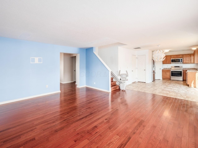 unfurnished living room with an inviting chandelier and light hardwood / wood-style flooring