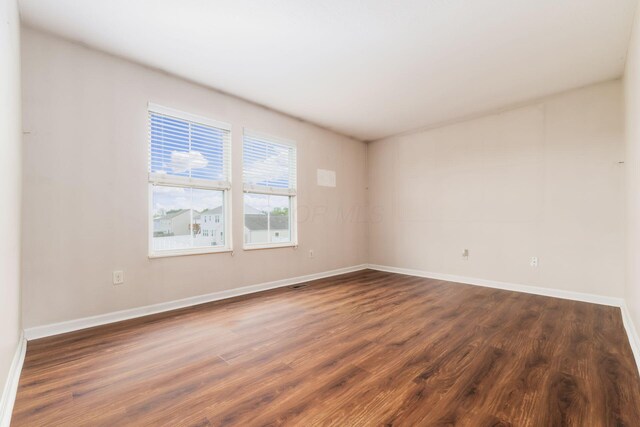 unfurnished room featuring dark wood-style flooring and baseboards