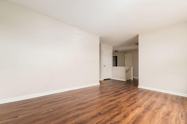spare room featuring baseboards, visible vents, and dark wood-type flooring