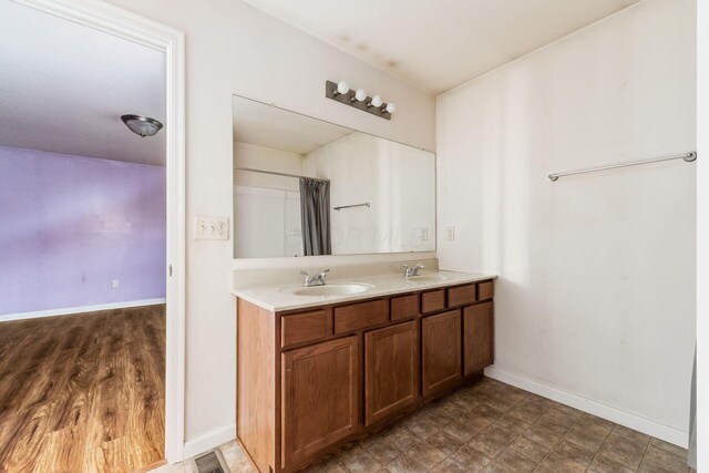 full bathroom featuring a sink, double vanity, baseboards, and visible vents