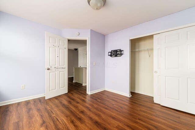 unfurnished bedroom with baseboards, a closet, and dark wood-style floors