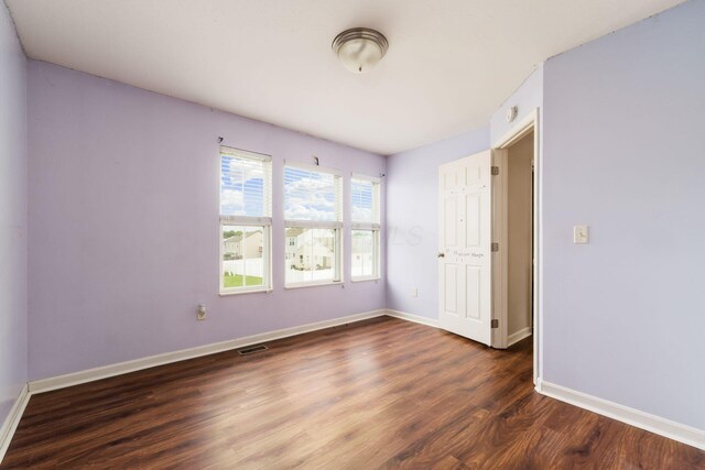 unfurnished bedroom with visible vents, wood finished floors, and baseboards