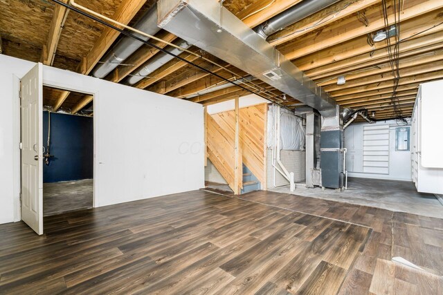 unfinished basement featuring heating unit, visible vents, wood finished floors, and electric panel
