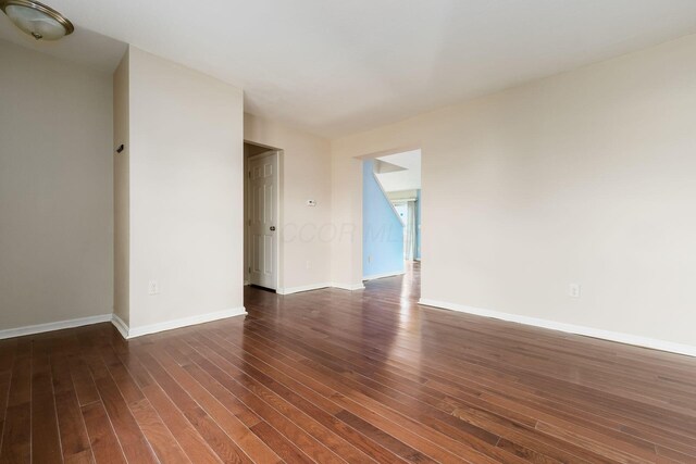 spare room with baseboards and dark wood-style floors