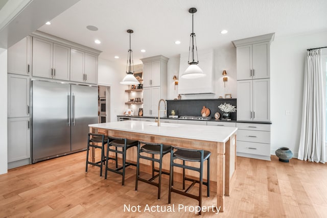 kitchen with sink, gray cabinetry, hanging light fixtures, a kitchen breakfast bar, and stainless steel appliances