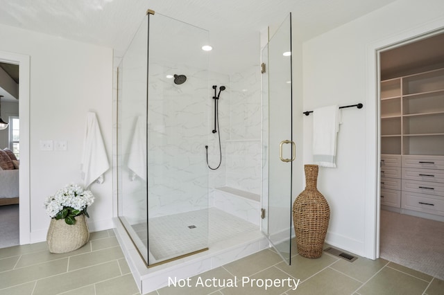 bathroom with a shower with door and tile patterned floors