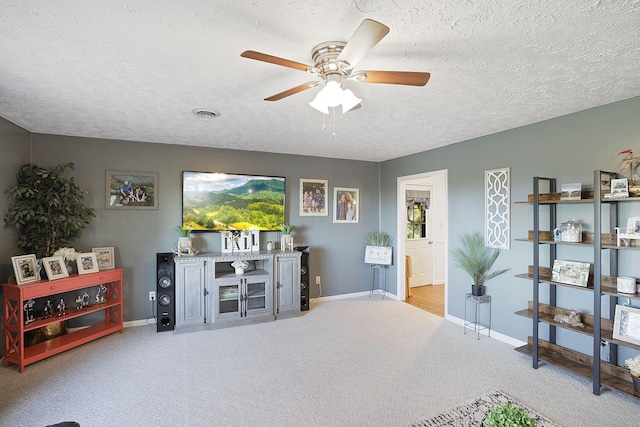 living room featuring ceiling fan, light colored carpet, and a textured ceiling