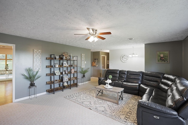 carpeted living room featuring ceiling fan with notable chandelier and a textured ceiling