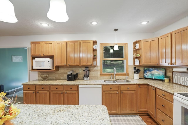 kitchen with sink, pendant lighting, white appliances, and backsplash