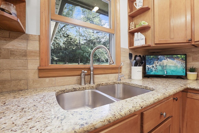 kitchen featuring sink, decorative backsplash, plenty of natural light, and light stone countertops