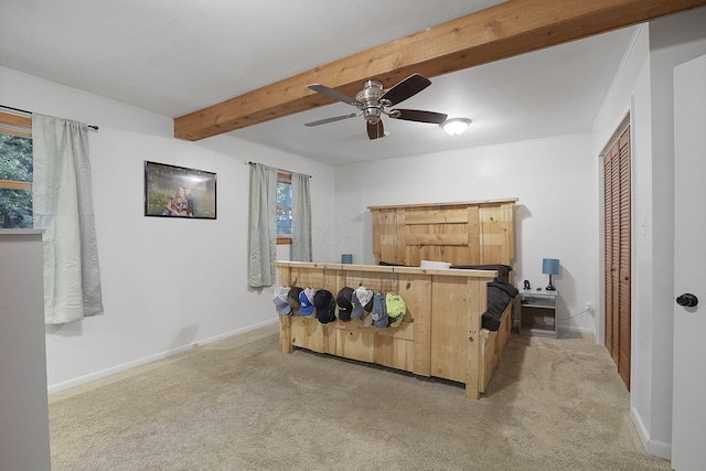 bedroom with ceiling fan, light colored carpet, a closet, and beam ceiling