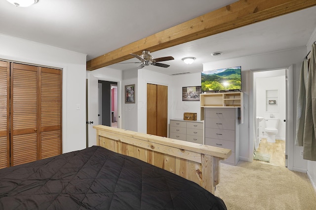 unfurnished bedroom with ensuite bathroom, ceiling fan, beamed ceiling, and light colored carpet