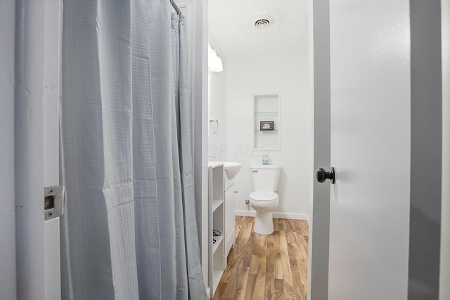 bathroom with toilet, vanity, and hardwood / wood-style floors