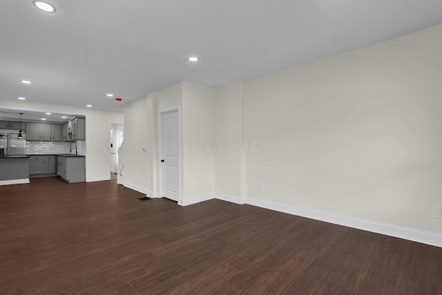 unfurnished living room with dark hardwood / wood-style flooring and sink