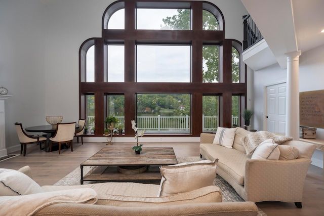 living room with ornate columns, a towering ceiling, and light hardwood / wood-style floors