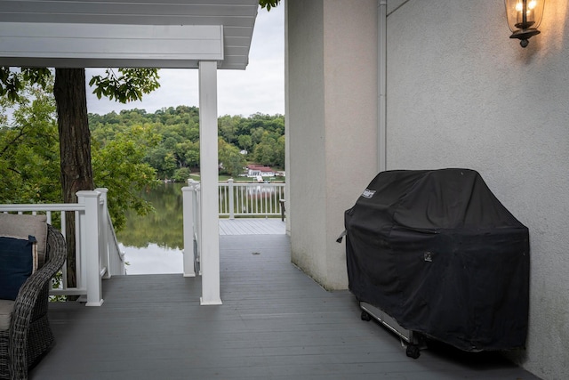 wooden terrace featuring area for grilling and a water view