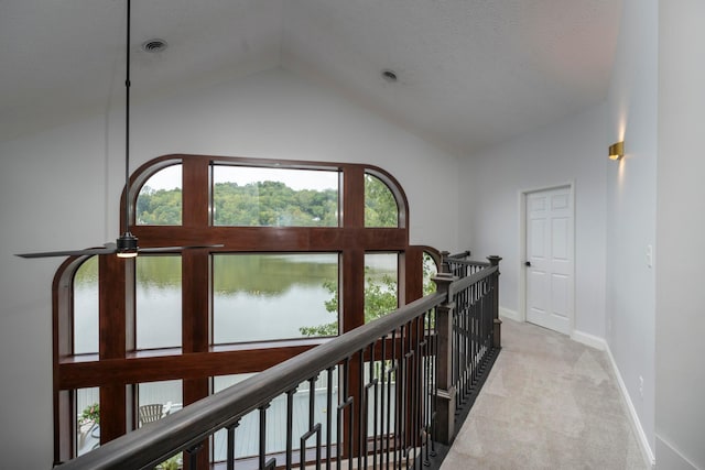 hall featuring light carpet, a water view, and lofted ceiling