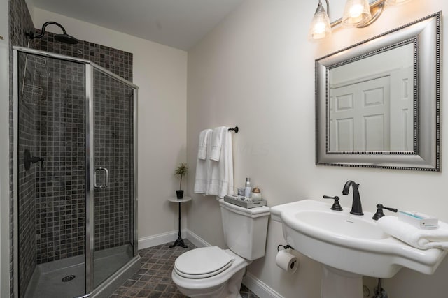 bathroom with toilet, a shower with shower door, and sink