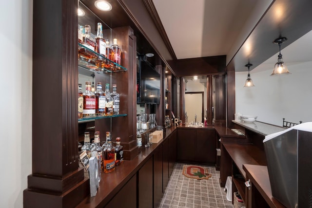 bar with dark brown cabinets, pendant lighting, and sink