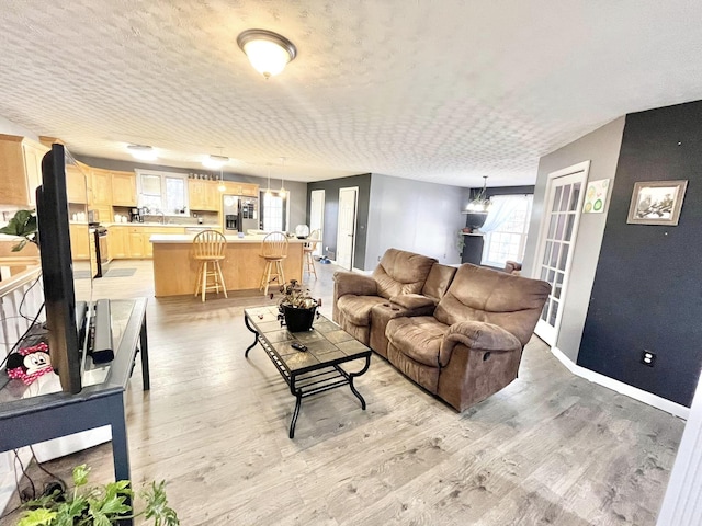 living room featuring light hardwood / wood-style floors, a textured ceiling, and a chandelier