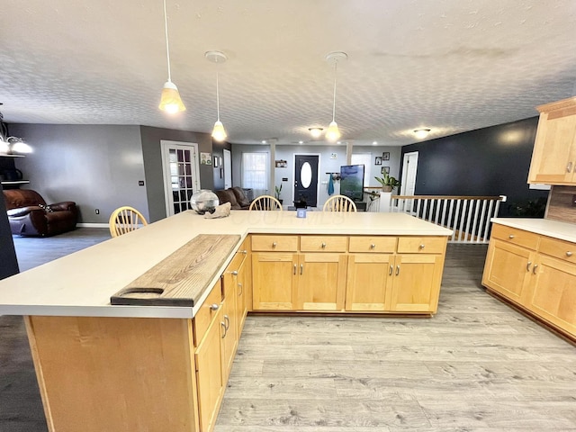 kitchen with light hardwood / wood-style flooring, a center island, hanging light fixtures, and light brown cabinets