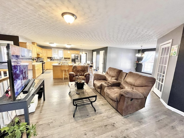 living room with a chandelier, a textured ceiling, and light hardwood / wood-style flooring