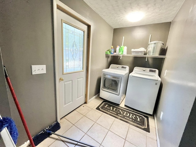 clothes washing area with washer and dryer, light tile patterned floors, and a textured ceiling