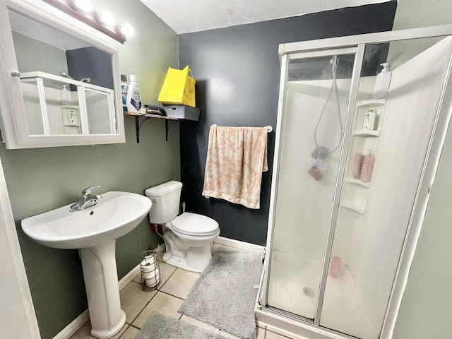 bathroom with tile patterned flooring, a shower with shower door, and toilet