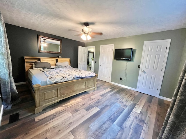 bedroom featuring a textured ceiling, ceiling fan, and dark wood-type flooring